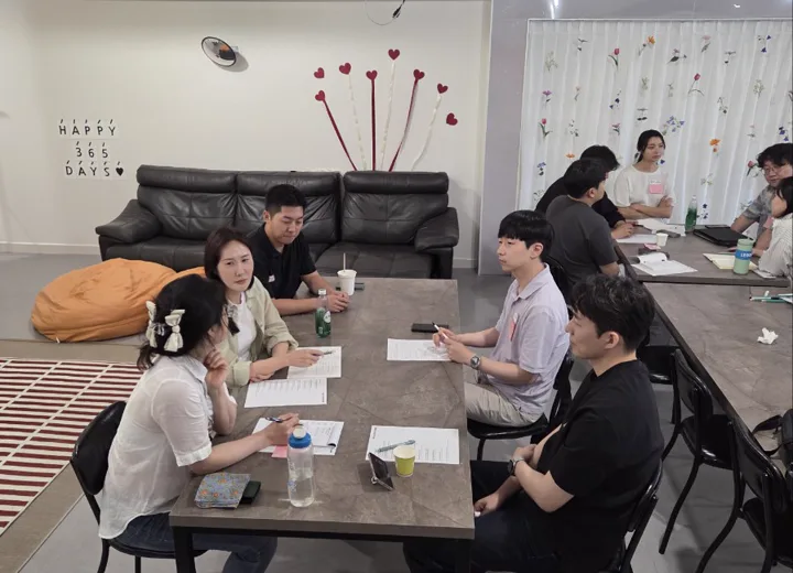 참가자들이 한 테이블에 둘러앉아 질문과 피드백을 나누는 모습